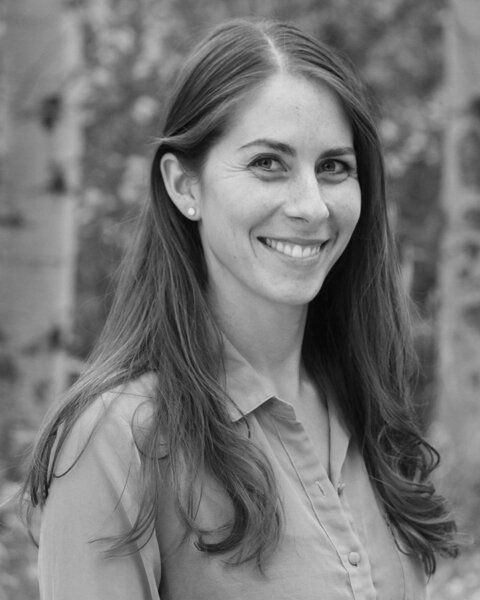A woman with long hair is smiling in a black and white photo.