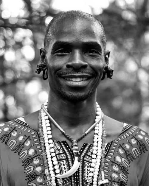 A black and white photo of a man wearing a necklace and earrings
