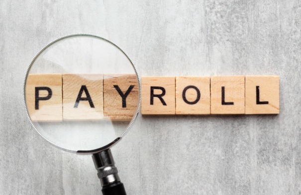 Two professionals review documents, charts, and a calculator at a desk in a bright, sunlit office.