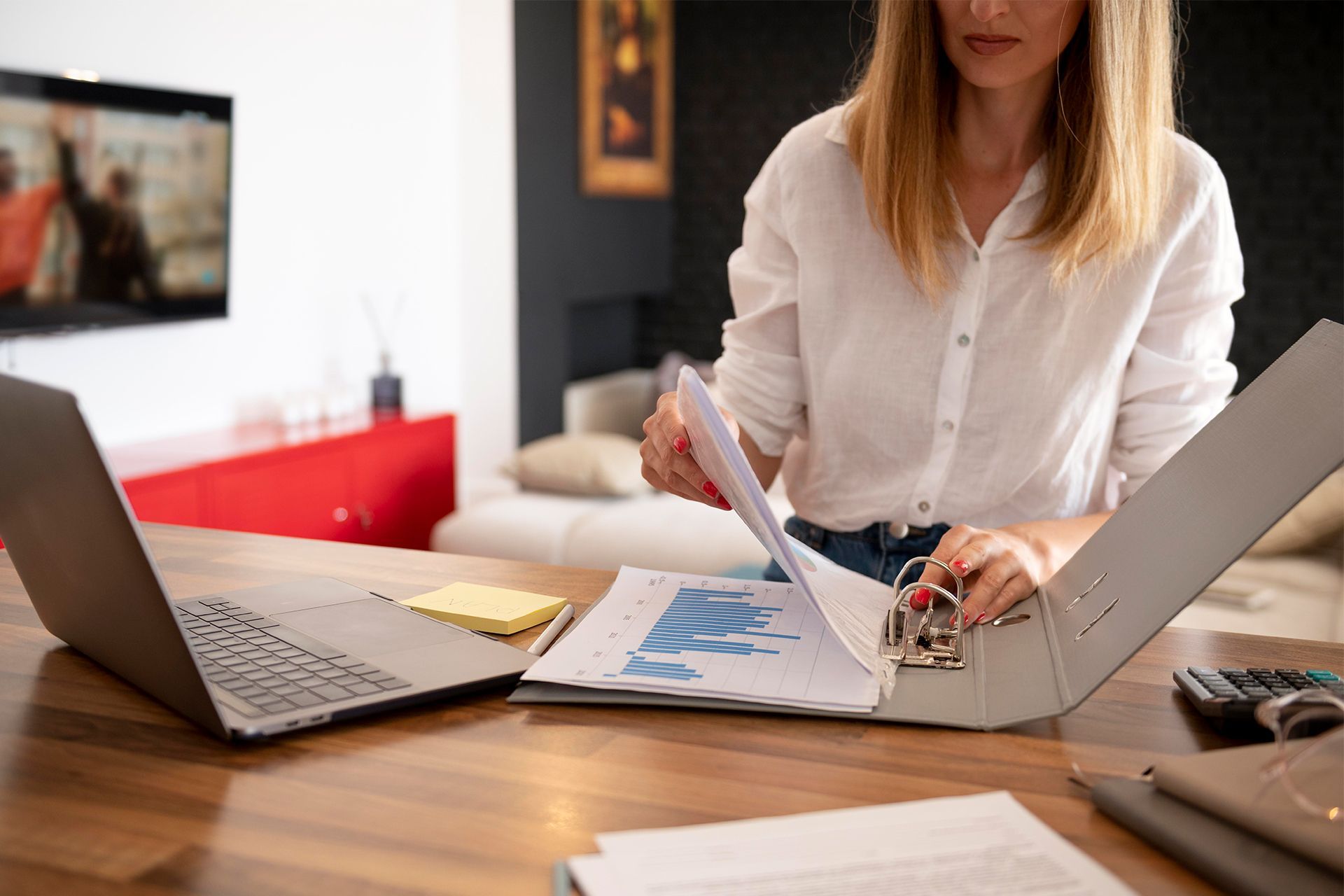 Woman at Desk Examining Documents in a Binder