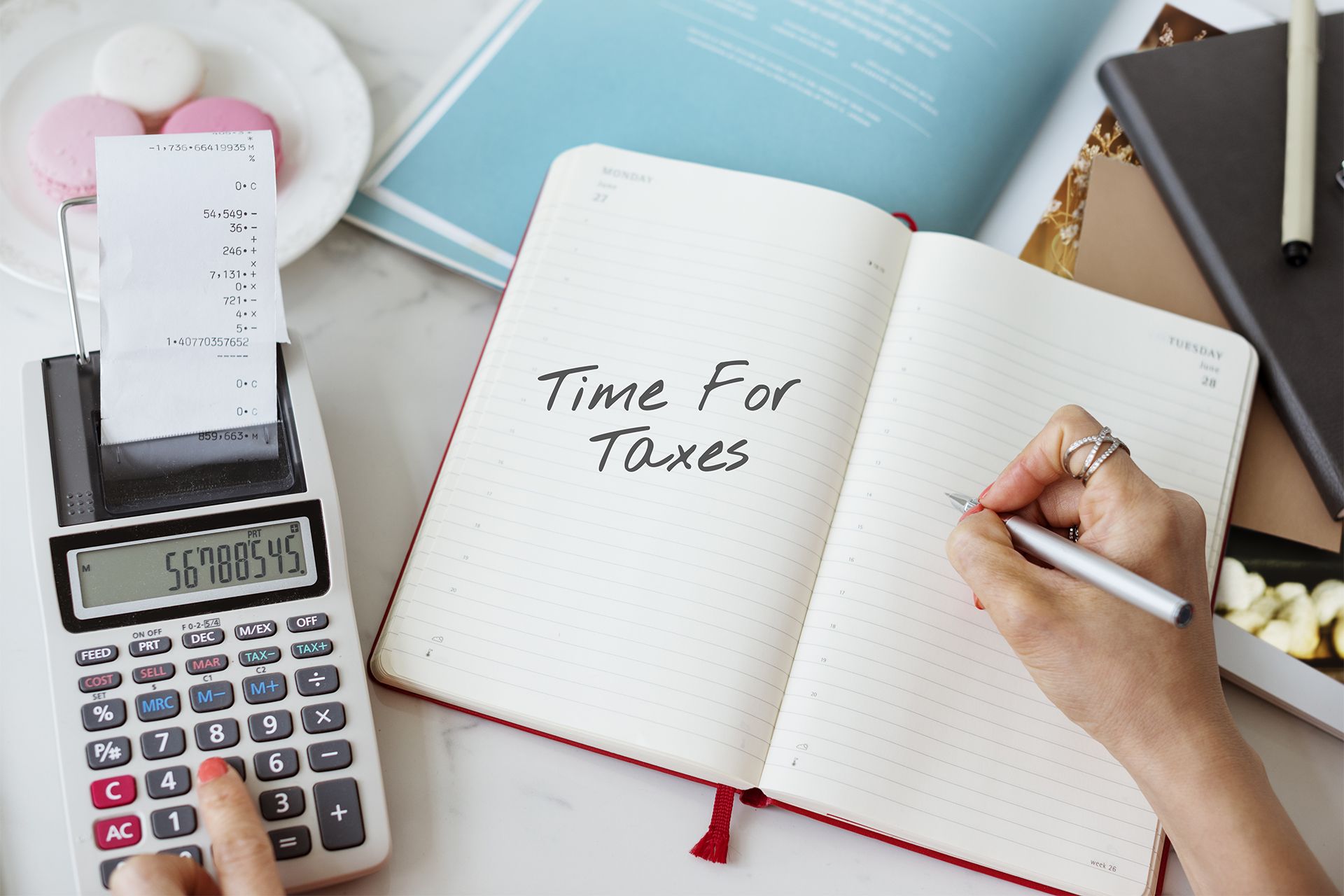 Person Calculating Taxes With Calculator and Notebook