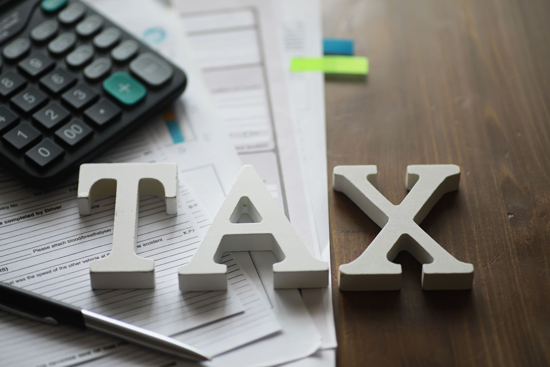 White tax letters on wooden table with calculator, papers, and pen.