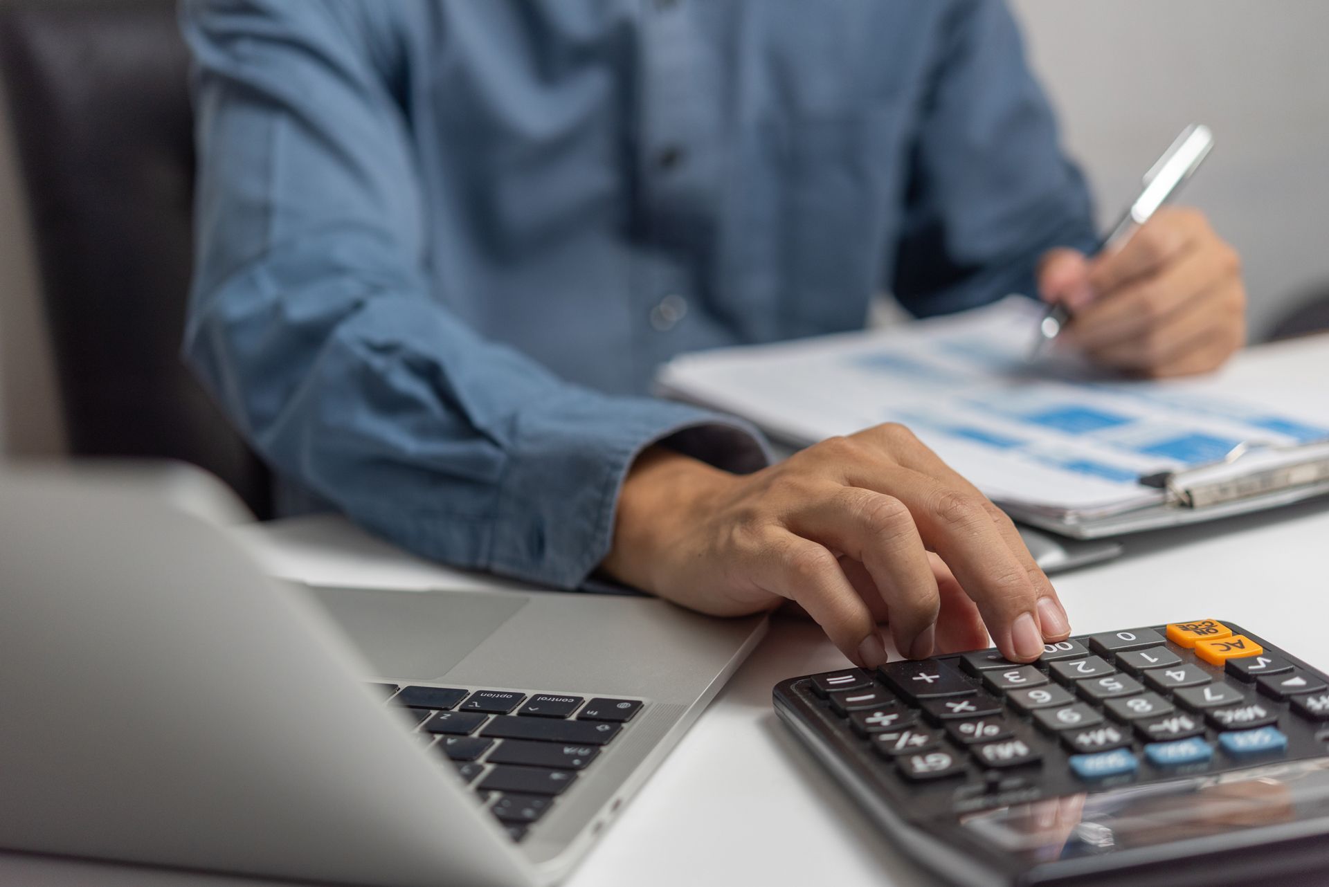 Calculator and Accounting Documents at Desk With Laptop Computer