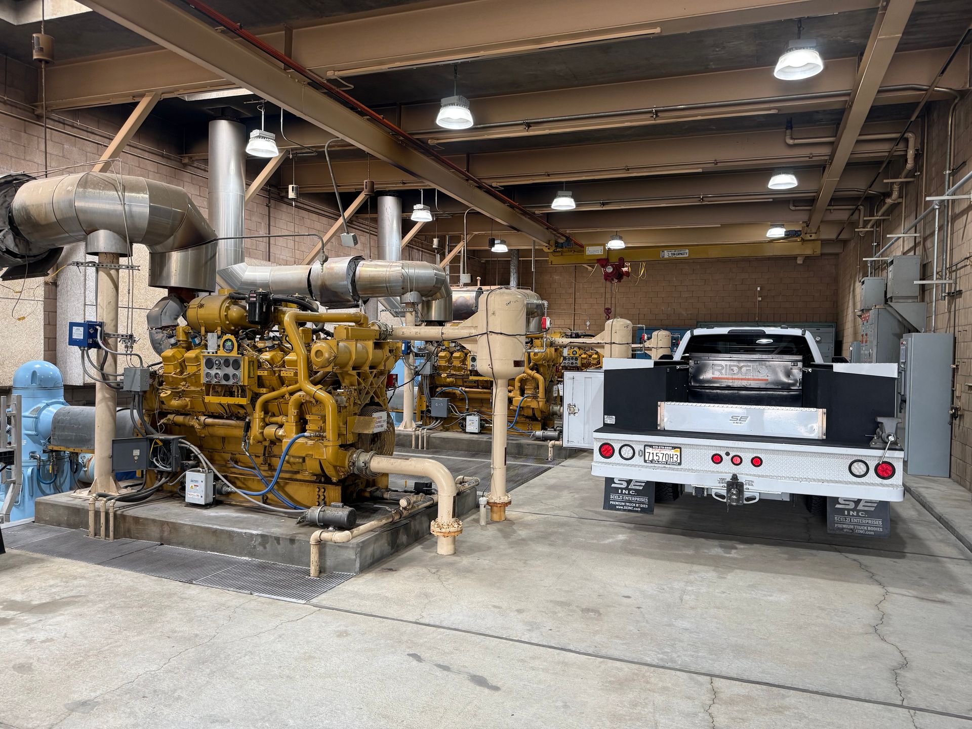 Yellow industrial generators inside a beige building, a white pickup truck parked in the doorway.
