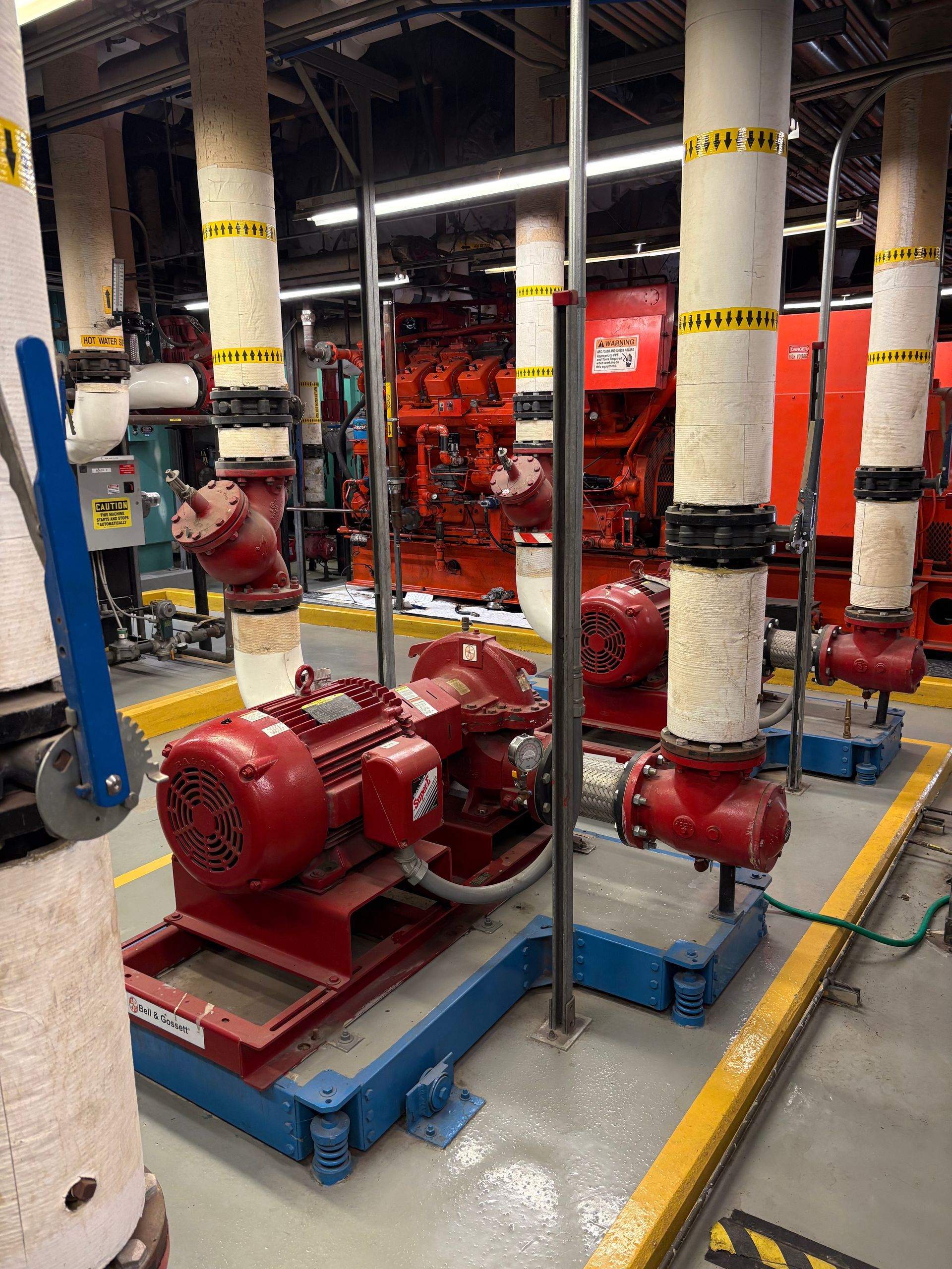 Red industrial pumps and pipes in a factory setting.