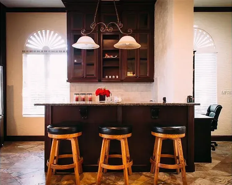 A kitchen with a bar and three stools.