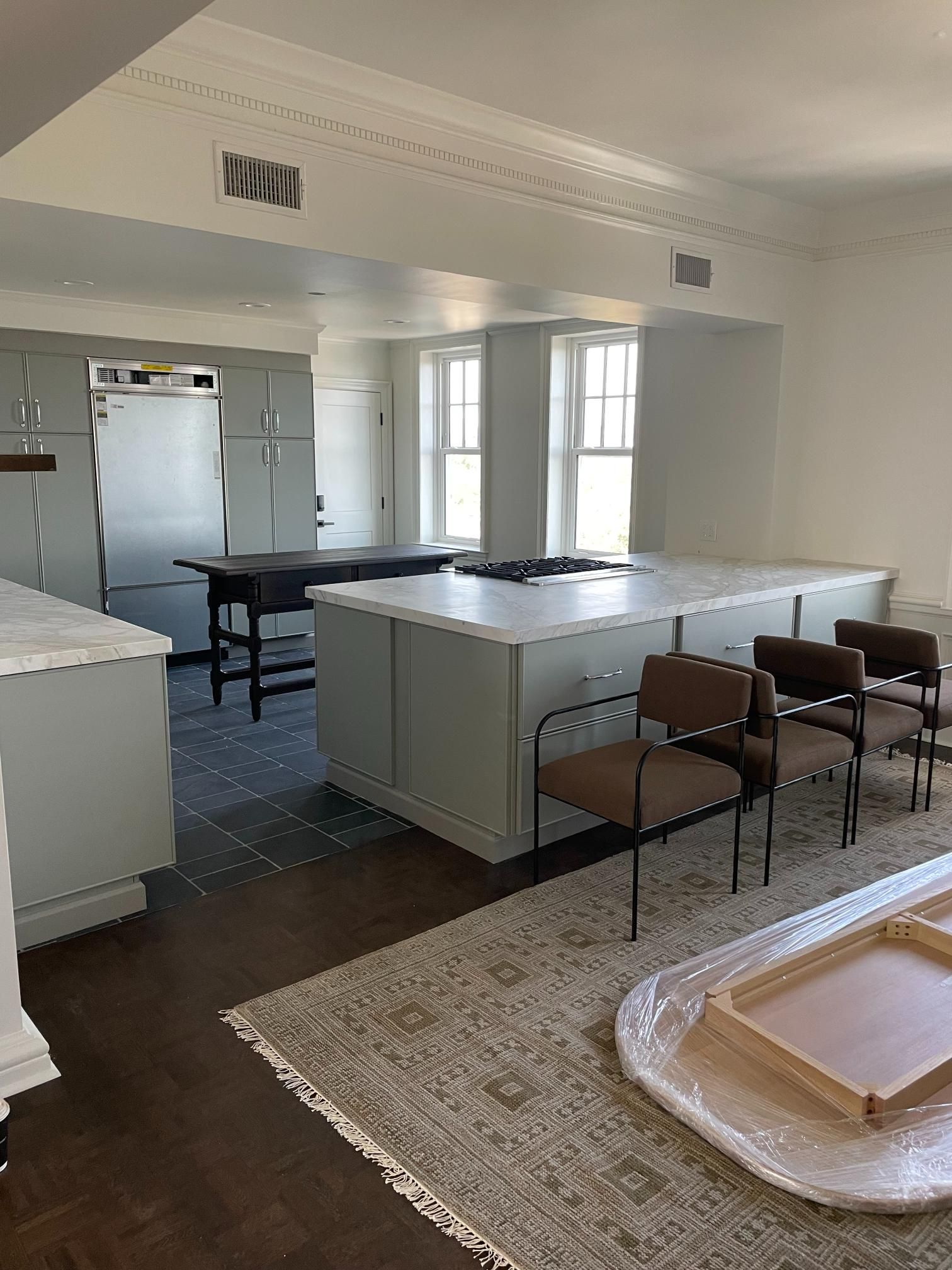 Modern kitchen with light blue cabinets, marble countertops, and stainless steel appliances.