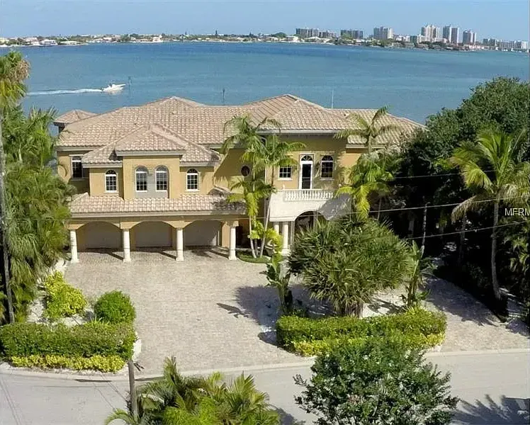 An aerial view of a large house overlooking a body of water