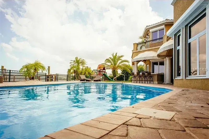 A large swimming pool in front of a large house.