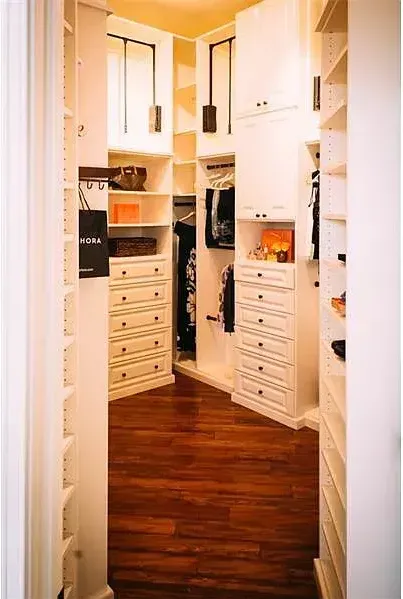 A walk in closet with lots of shelves and drawers