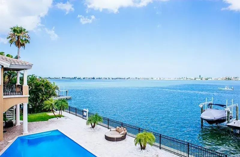 A large house with a swimming pool next to a body of water.