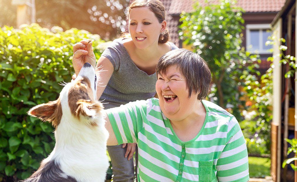 Happy Person Playing With Her Dog — Disability Support in Townsville, QLD