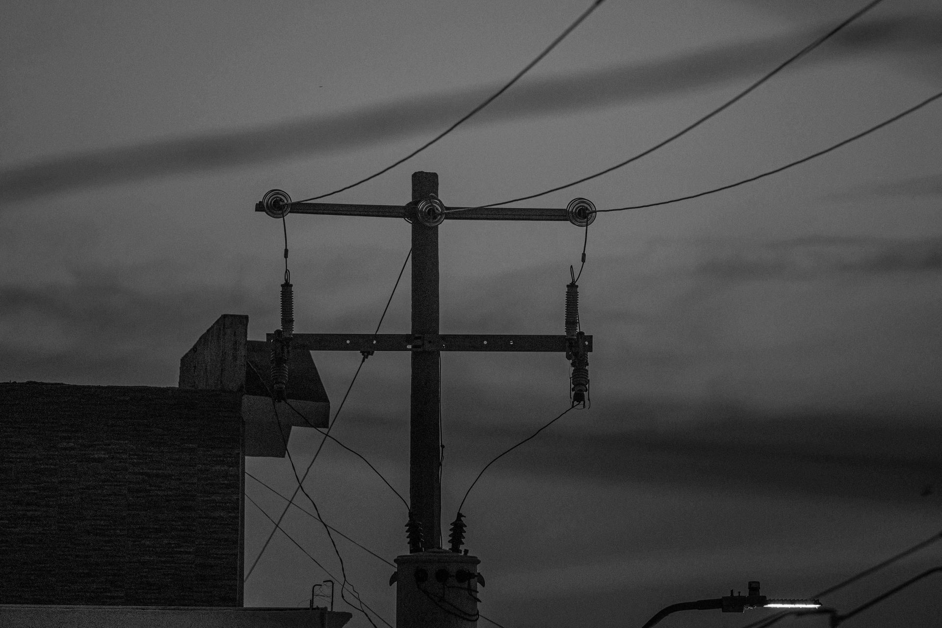 Power lines on a wooden utility pole against a cloudy, dark sky.