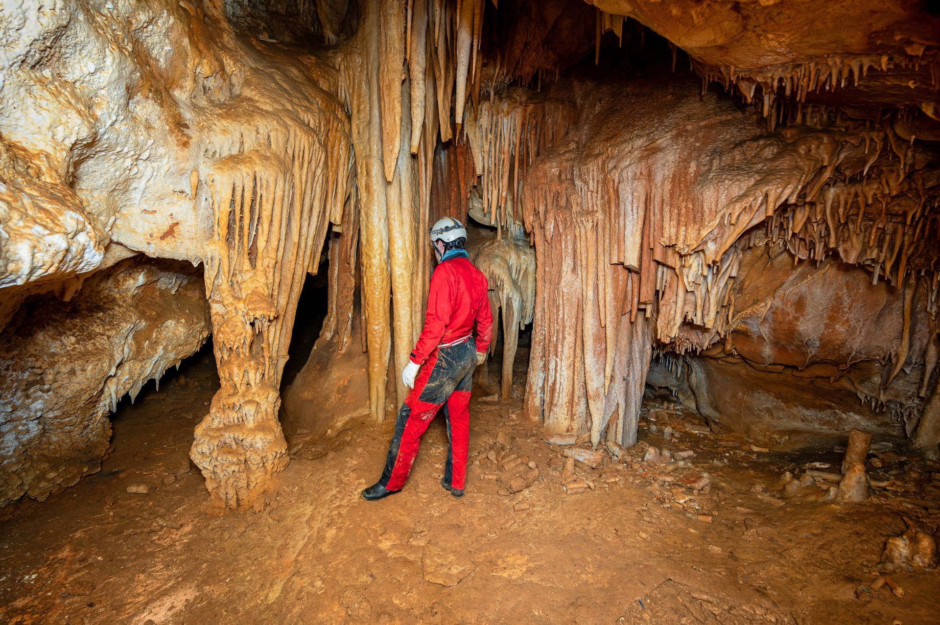A man in a red suit is standing in a cave.