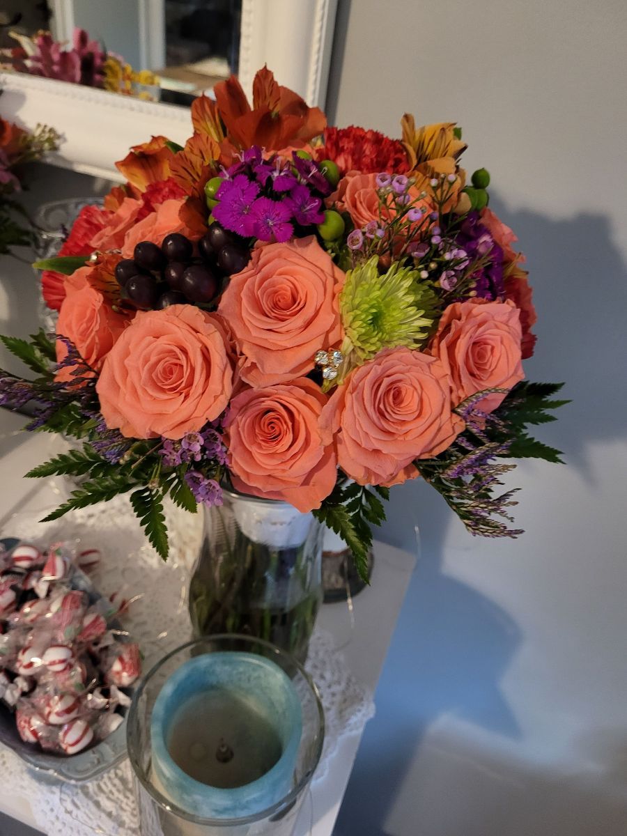 a vase of flowers sits on a table next to a candle