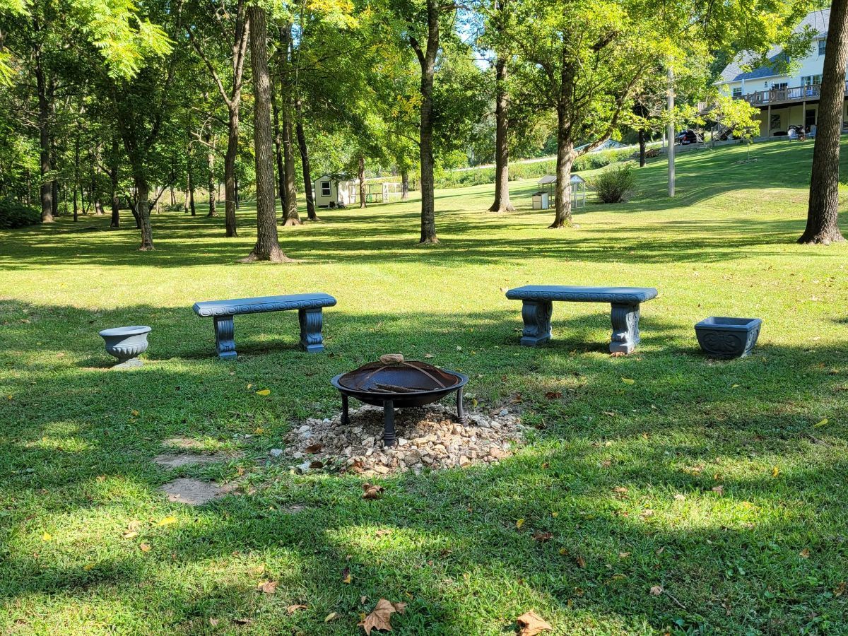 a fire pit sits in the middle of our lush green backyard