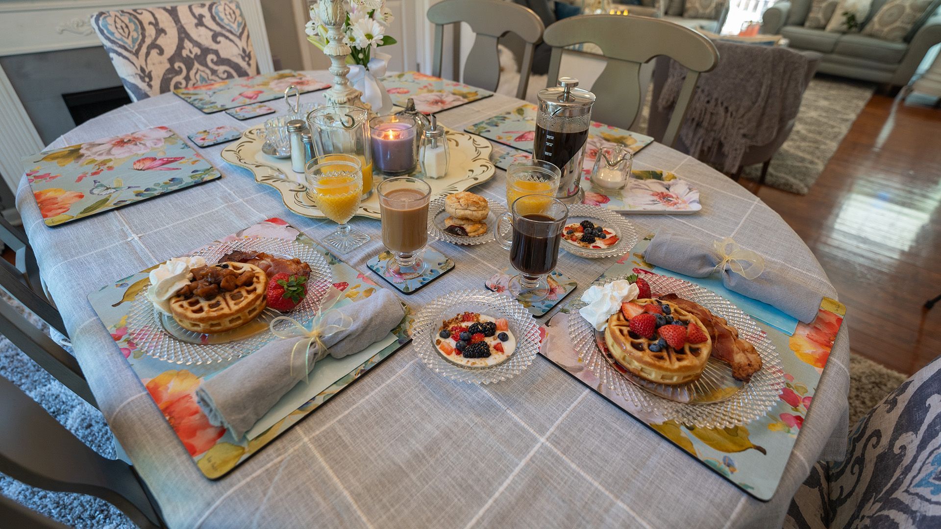 a table with plates of food and drinks including a french press, waffles and coffee