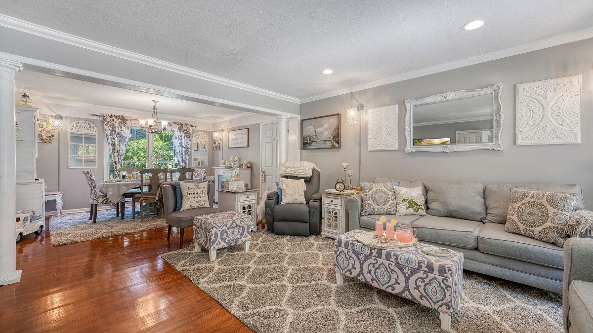 a living room with a couch and chairs and a dining room in the background