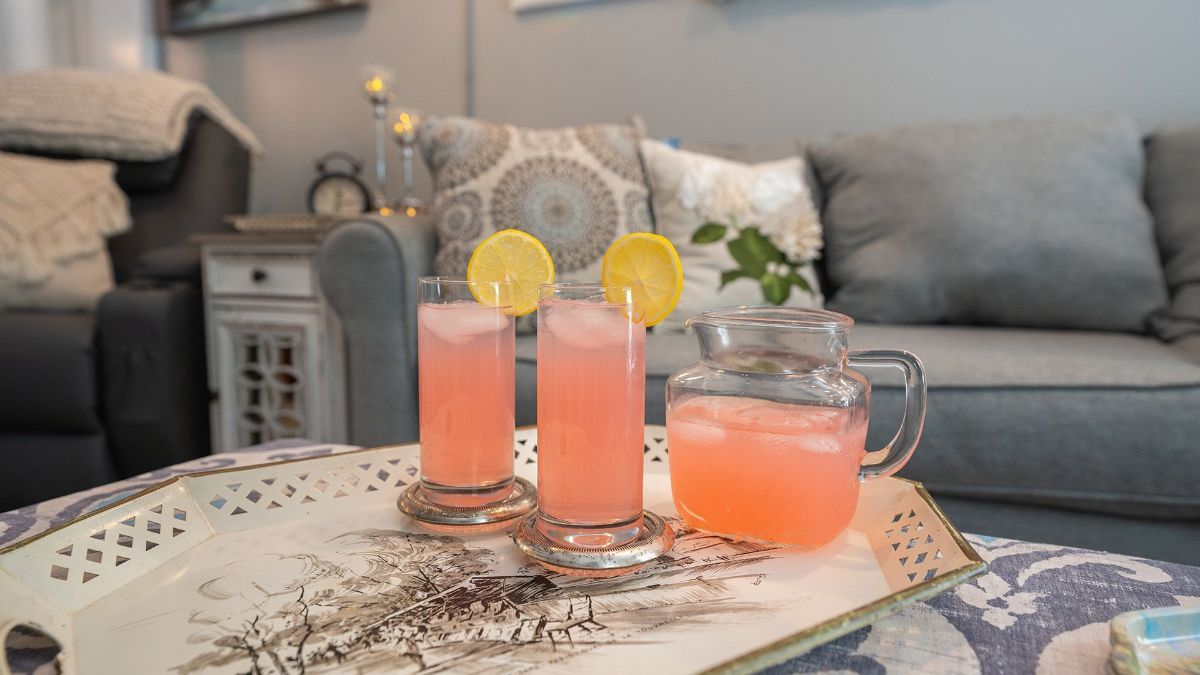 a pitcher and two glasses of pink lemonade on a tray