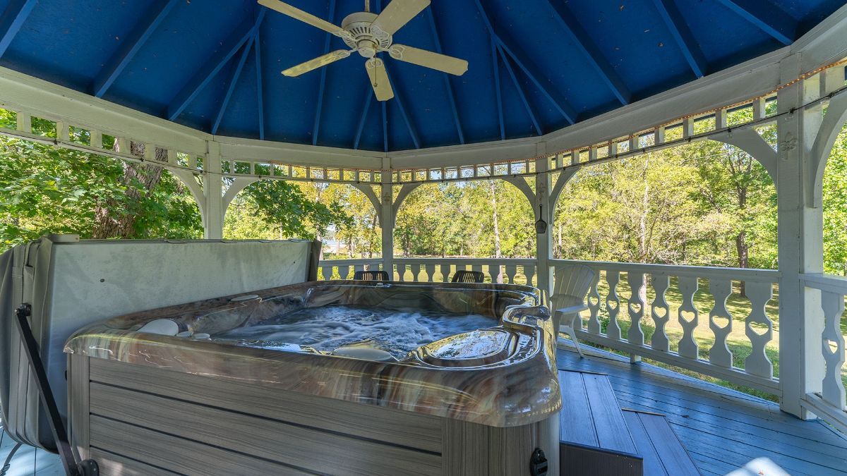 a gazebo with a hot tub and a ceiling fan