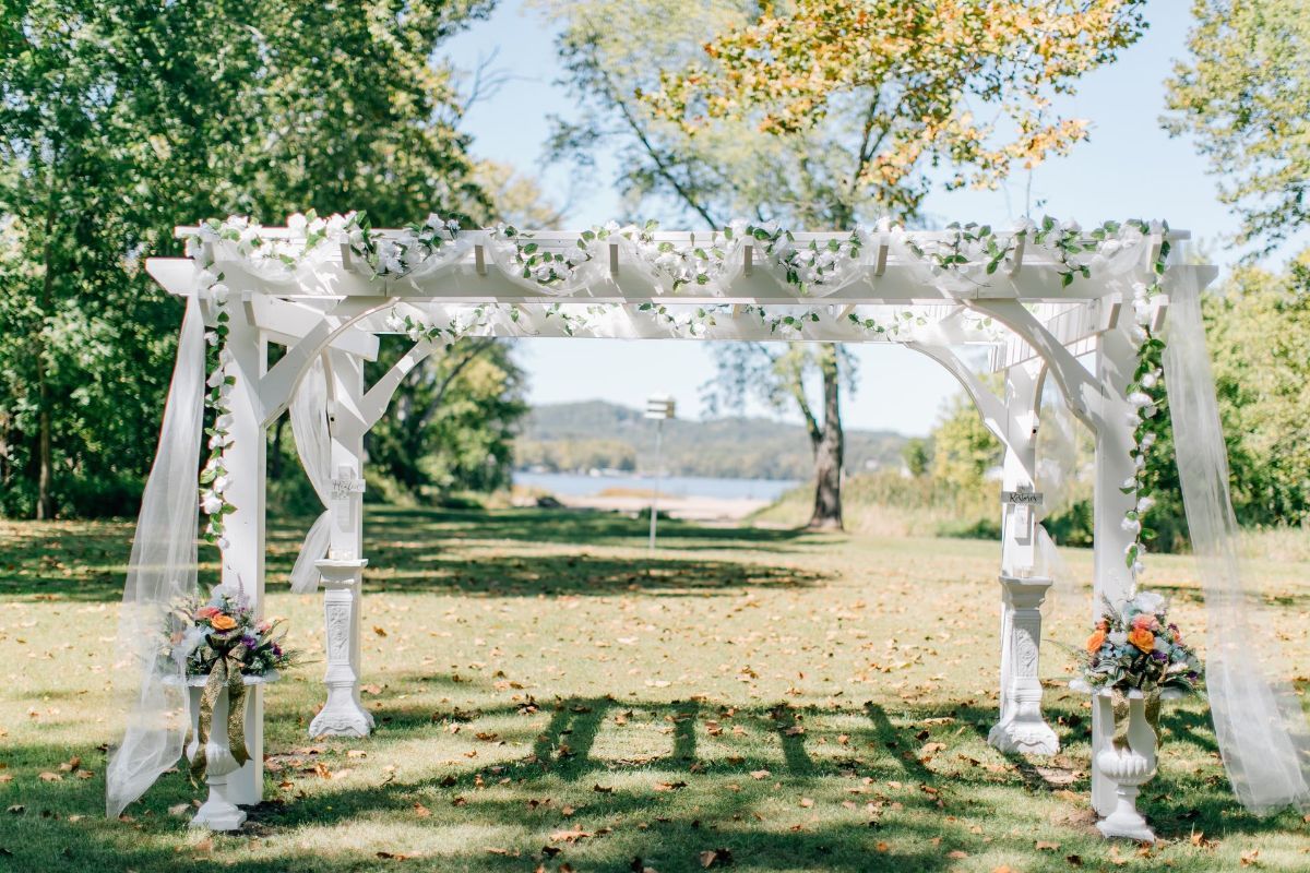 a white pergola with flowers and leaves on it
