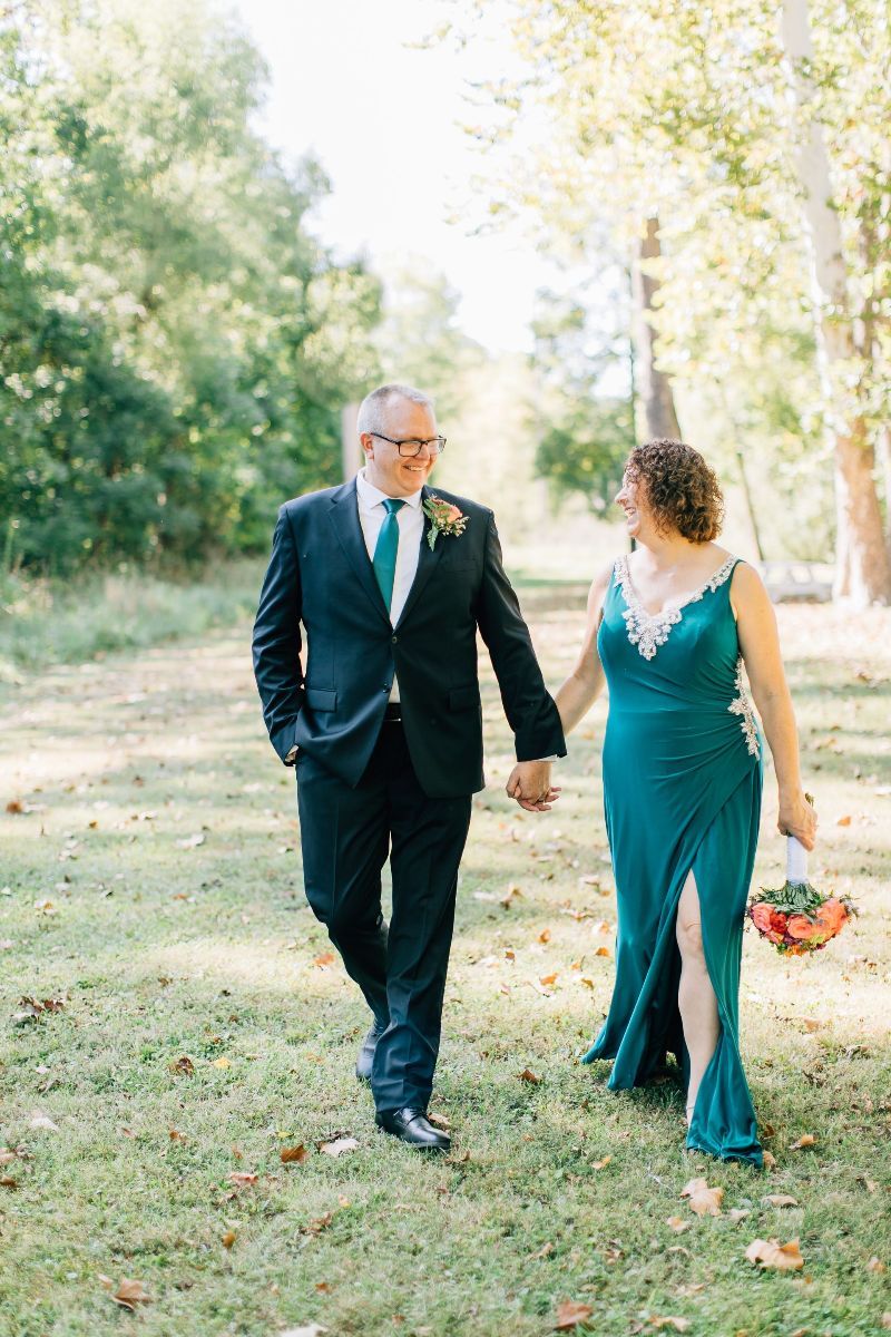 a man in a suit and tie is walking with a woman in a green dress