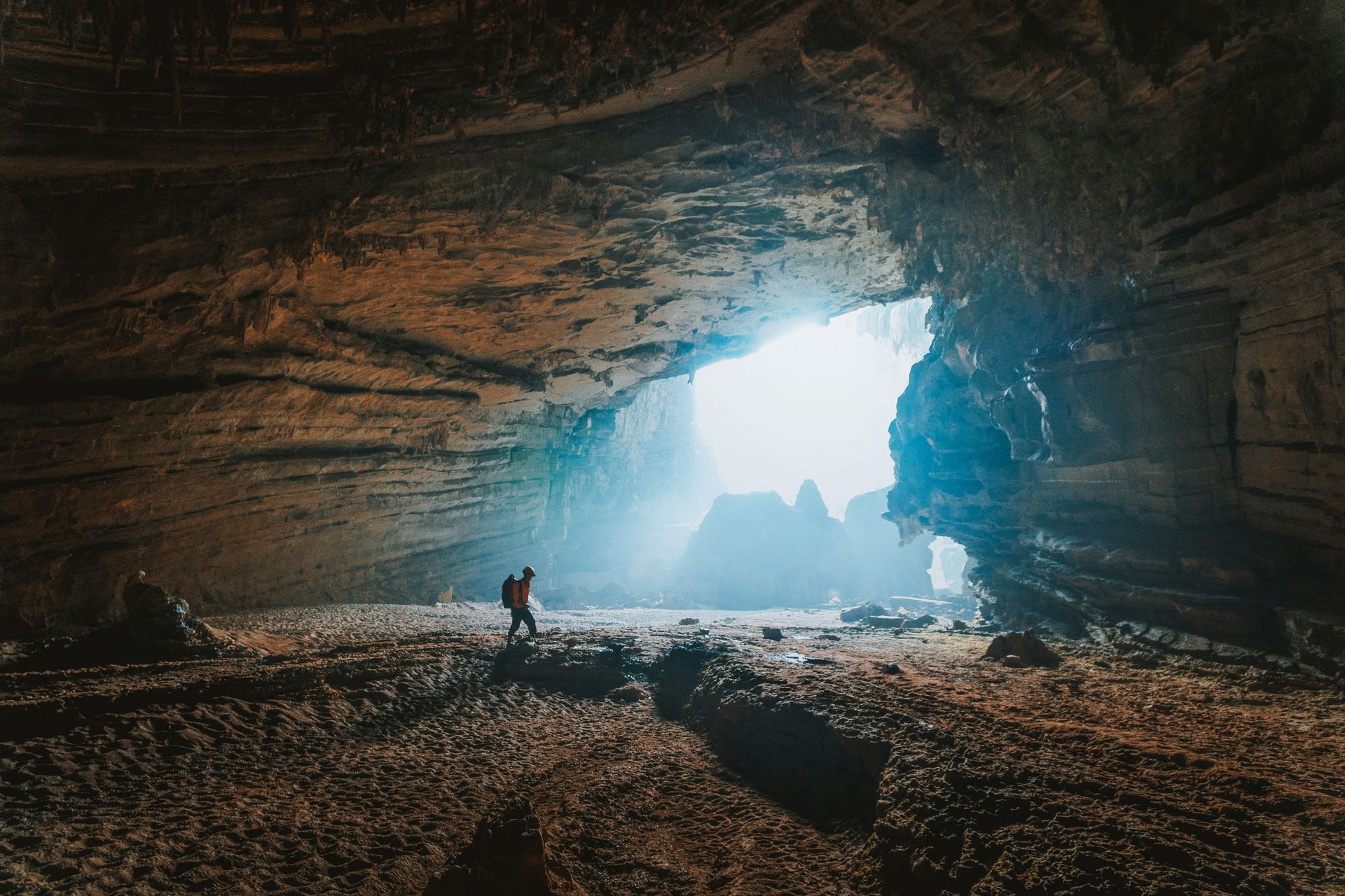 A man is standing in the middle of a cave.