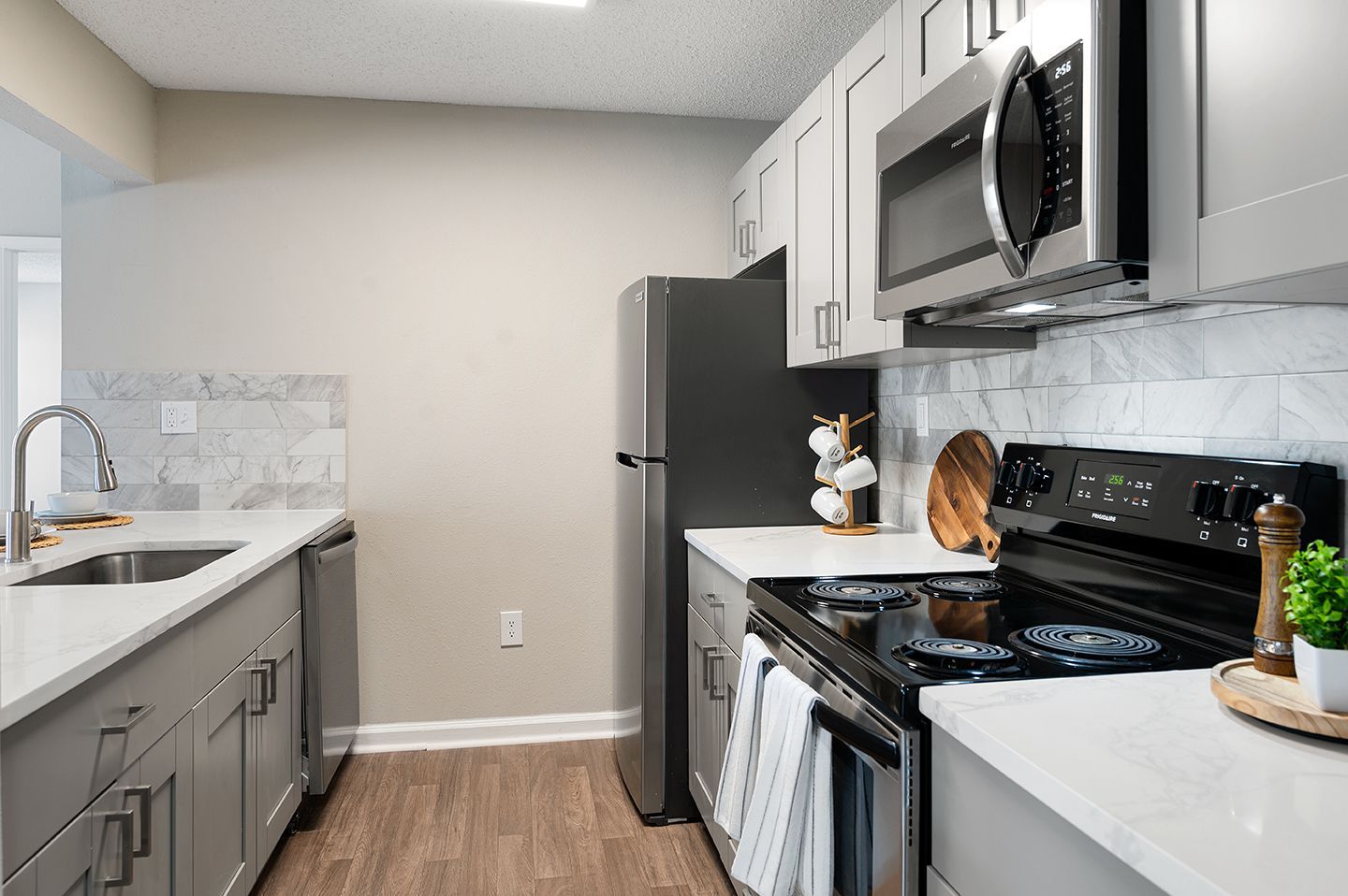 Modern kitchen with gray cabinets, stainless steel appliances, and white countertops at Station Heights in Alpharetta, GA.