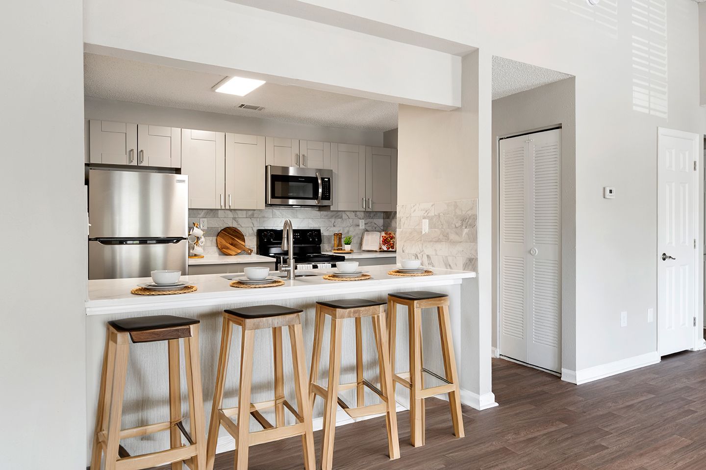 Modern kitchen with stainless steel appliances, breakfast bar with stools, and white cabinets at Station Heights in Alpharetta, GA.