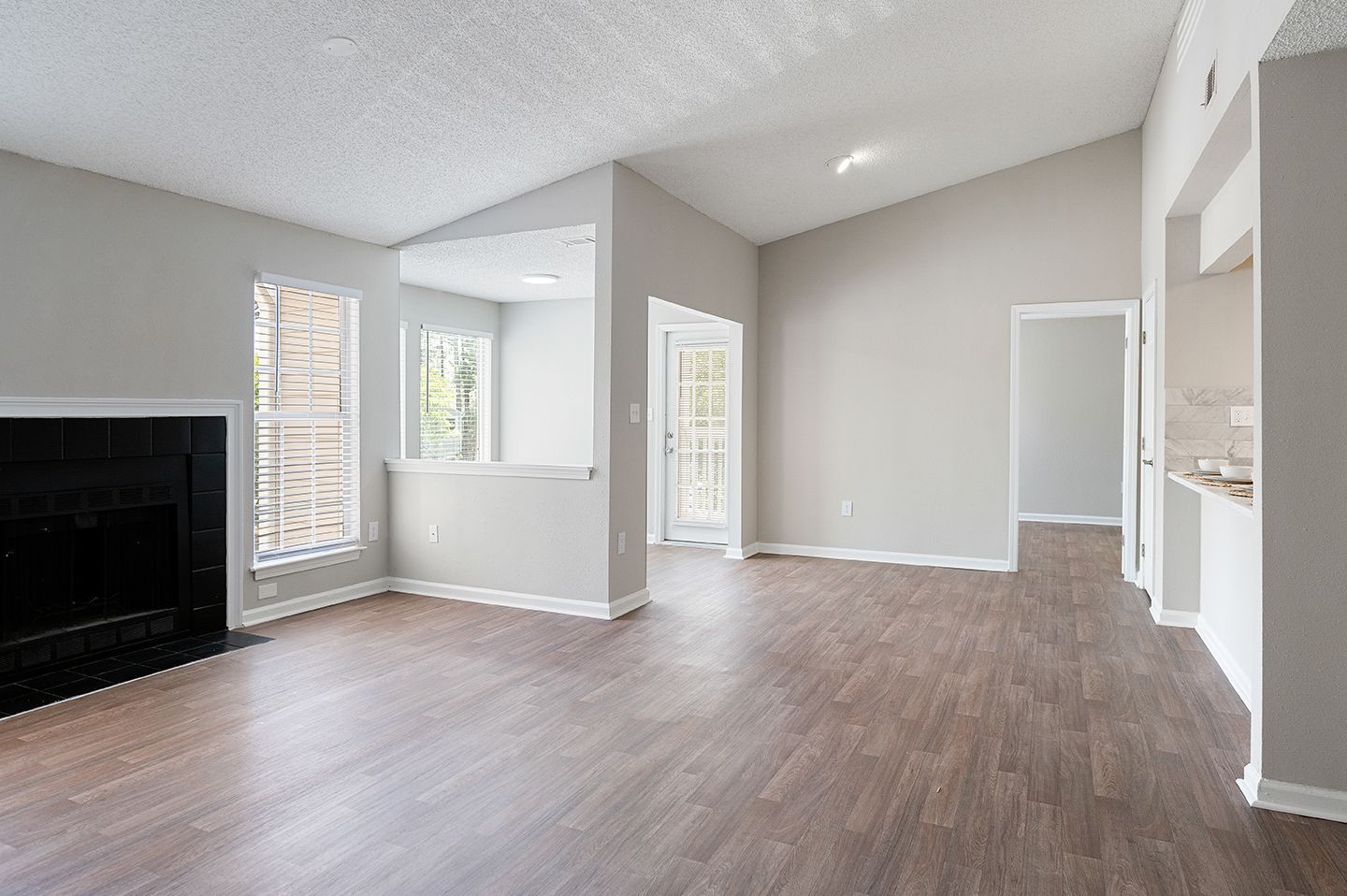 Empty living room with fireplace, light gray walls, and wood-look flooring at Station Heights in Alpharetta, GA.