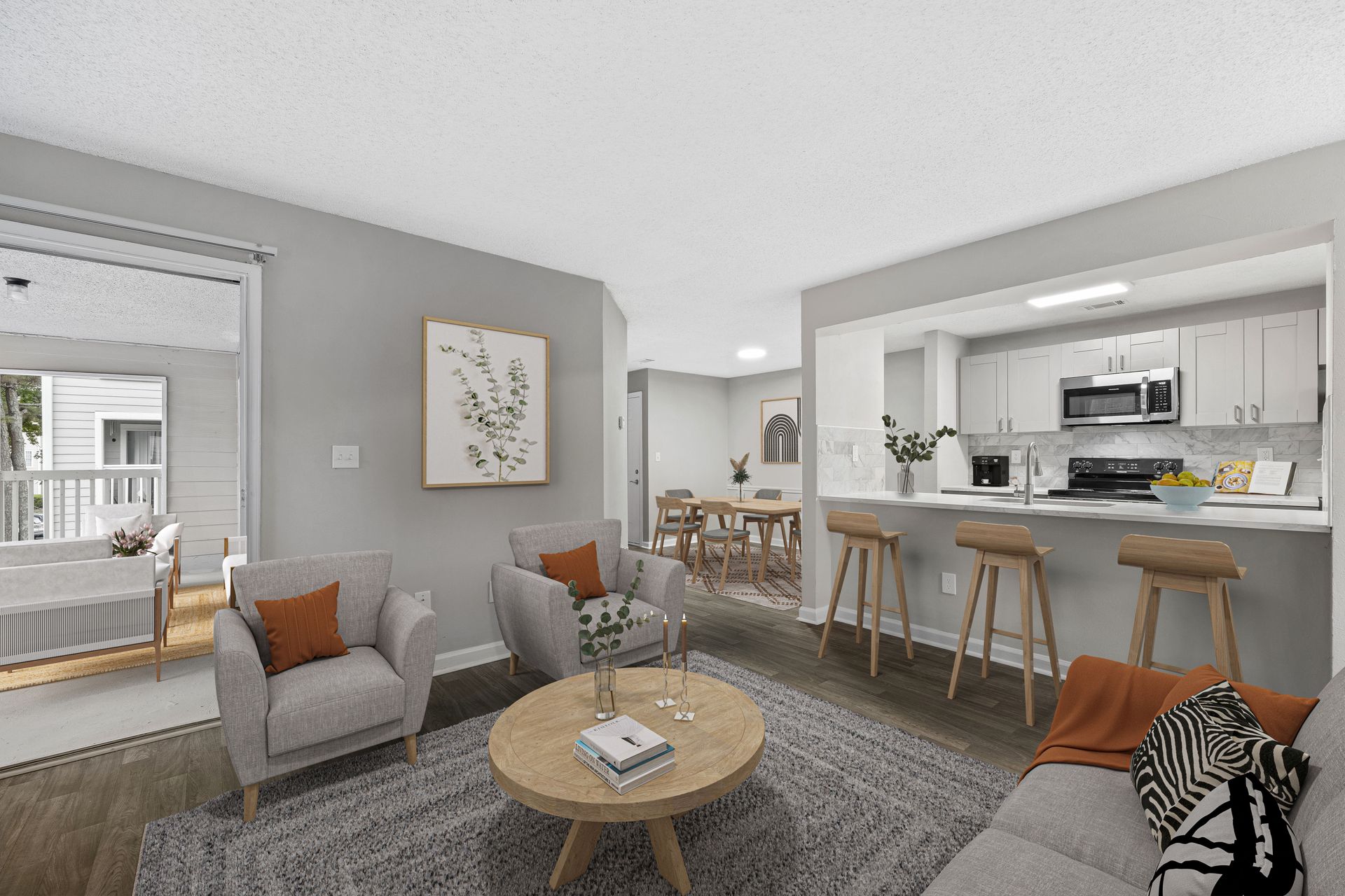 Living room and kitchen in apartment. Gray walls, light wood furniture, open layout, natural light at Station Heights in Alpharetta, GA.