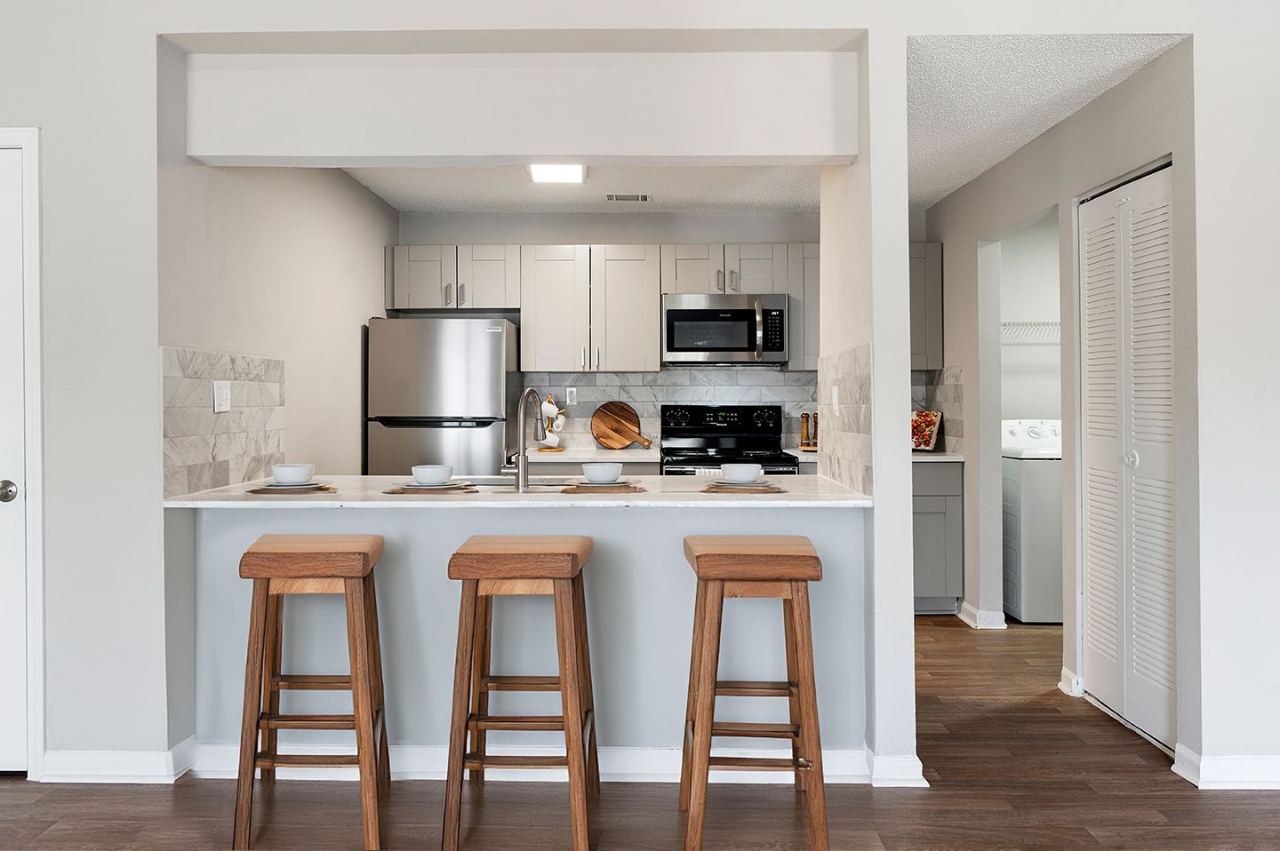 Kitchen with bar stools, stainless steel appliances, and gray cabinets at Station Heights in Alpharetta, GA.