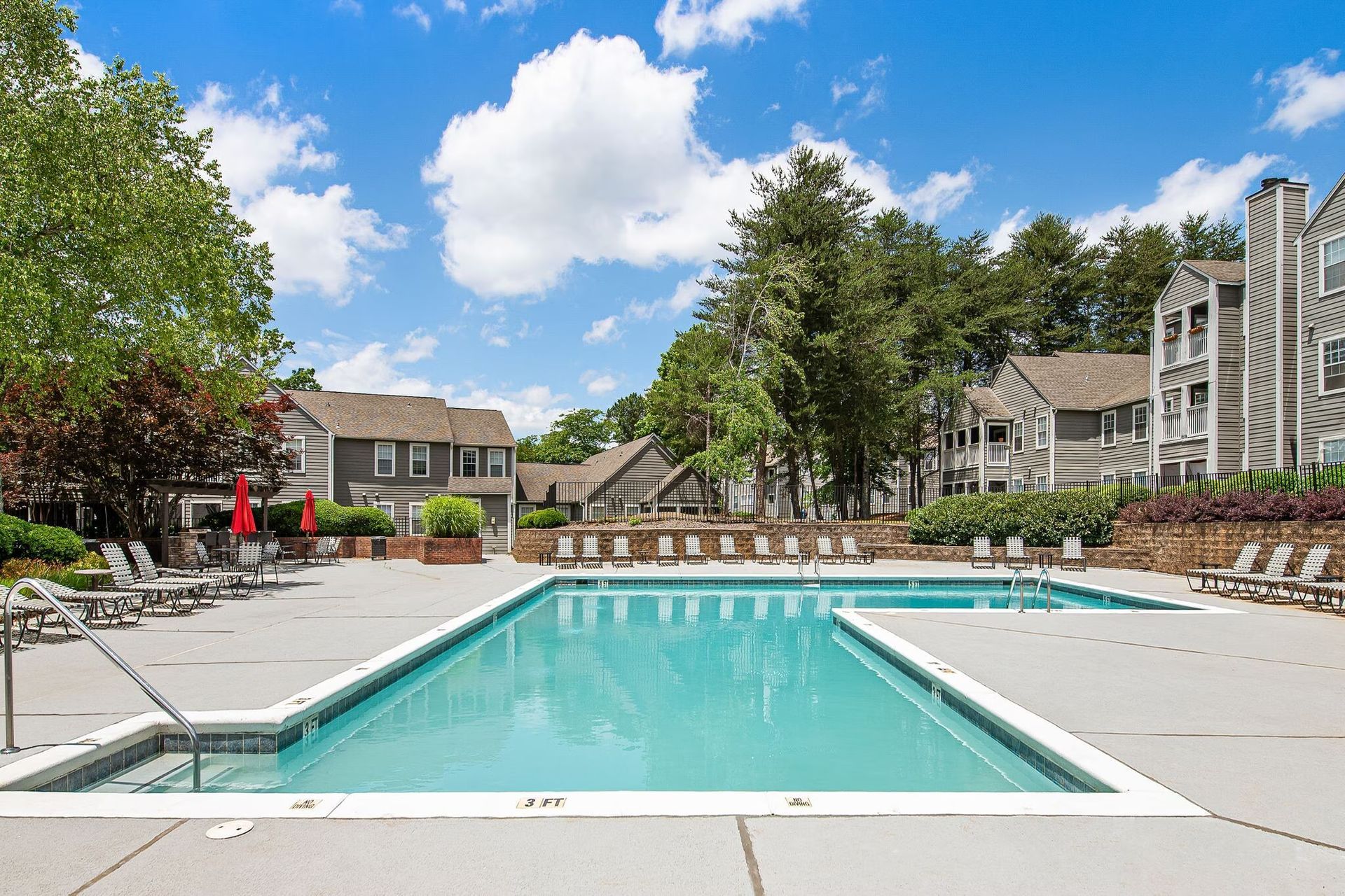 Swimming pool in front of apartment buildings on a sunny day at Station Heights in Alpharetta, GA.