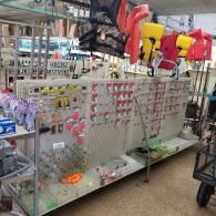 A retail display rack featuring a pegboard wall filled with small hardware items, with life vests hanging above.