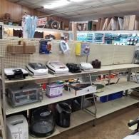 Shelves in a thrift store filled with various kitchen appliances, including toaster ovens, blenders, and irons.
