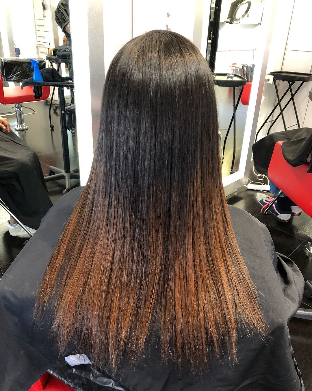 Hair styled with a dark to light ombre, straight with a salon backdrop.