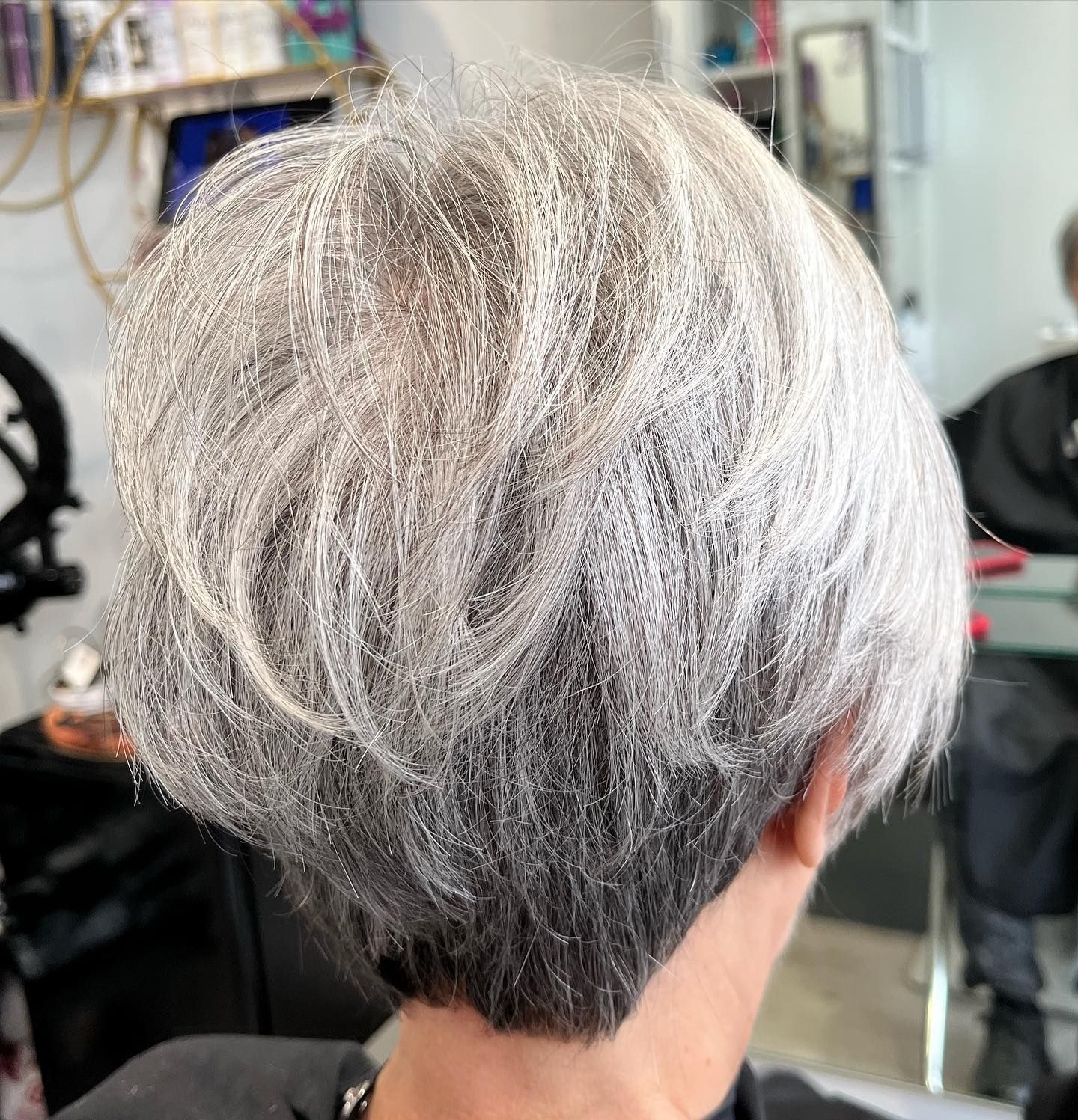 Close-up of styled, short, gray hair. Darker roots with light, layered top.
