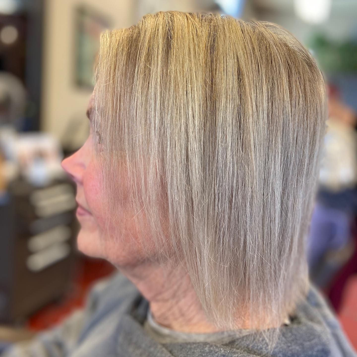Woman with light blonde hair, side profile in salon setting.