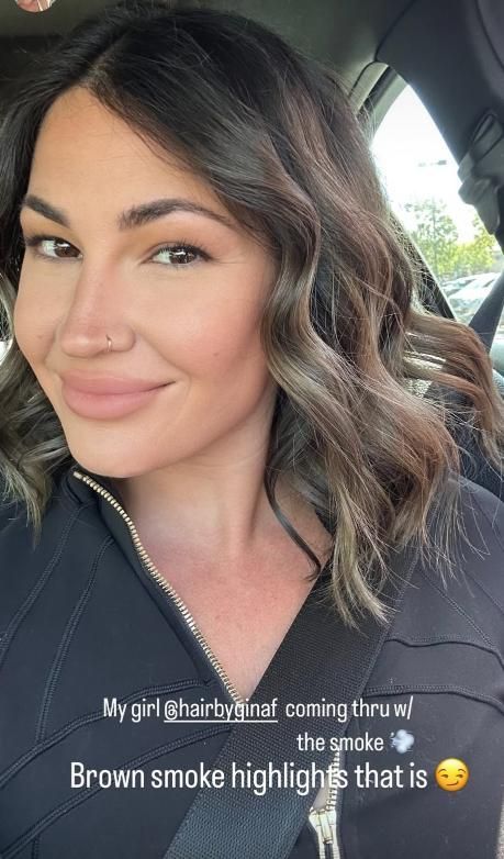 Woman with brown smoke highlights smiles inside a car.