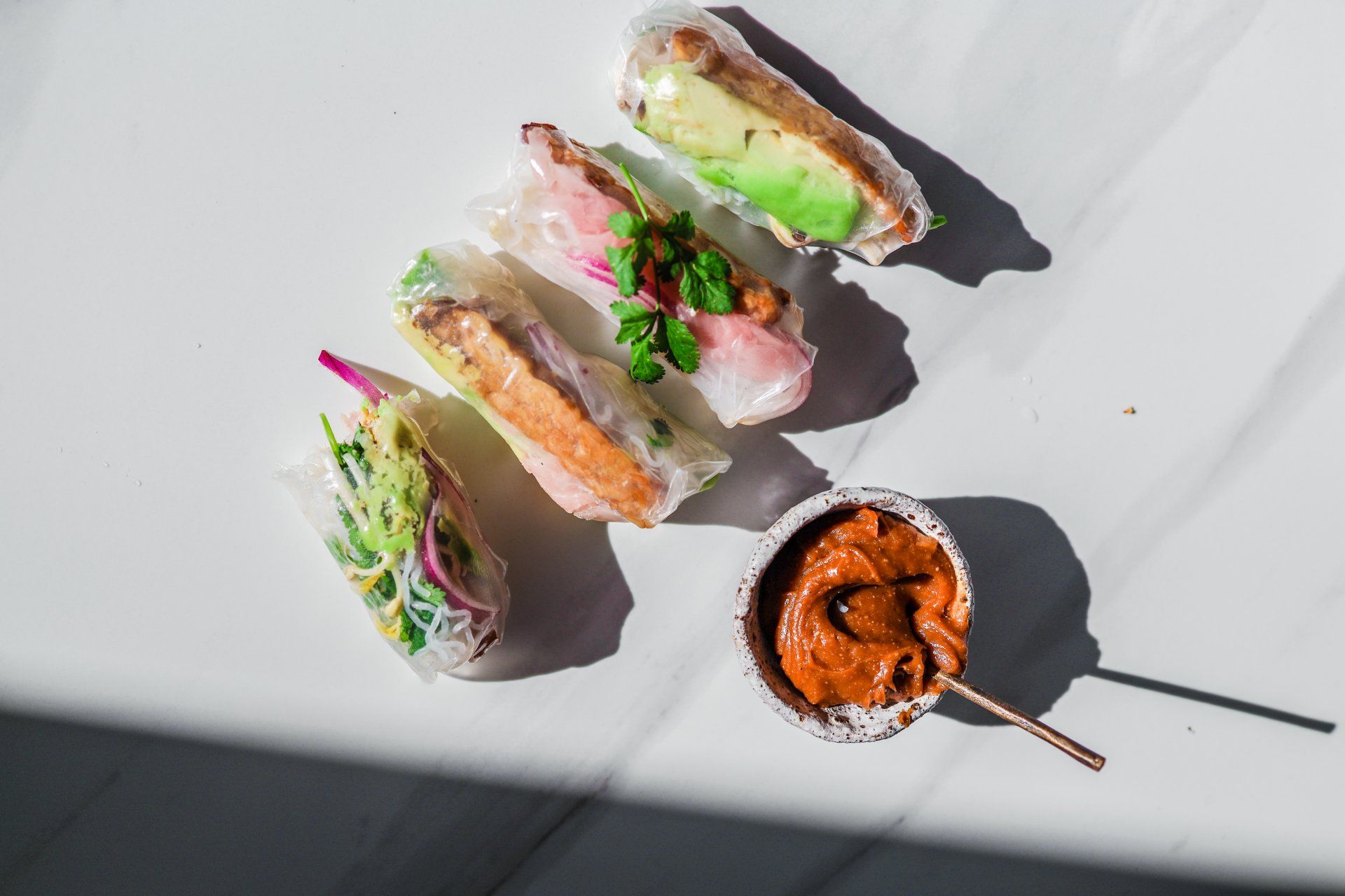 A white table topped with rolls and a bowl of sauce.