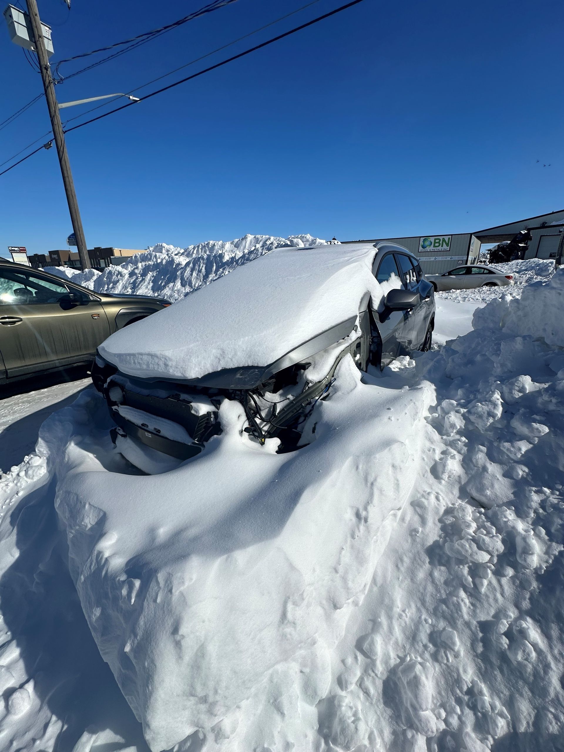 A car is covered in snow in a parking lot