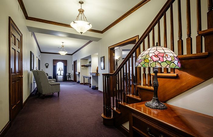 A long hallway with purple carpet and chairs and a desk.