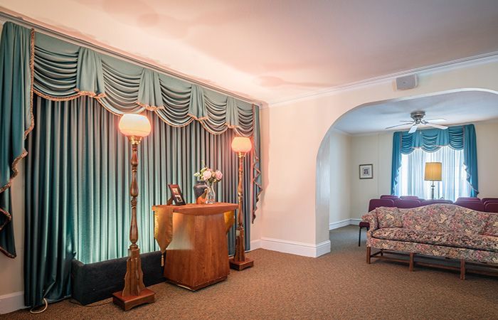 A room with rows of wooden chairs and a piano in the background.