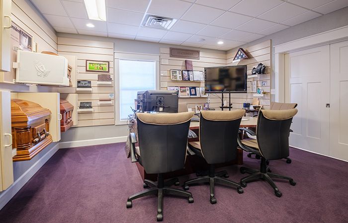 A conference room with a table and chairs and a television.