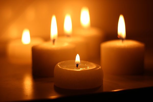 a group of lit candles are sitting on a table in a dark room .