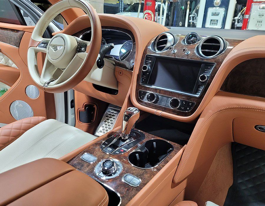 Tan Bentley car interior with leather upholstery, wood trim, and a center console.