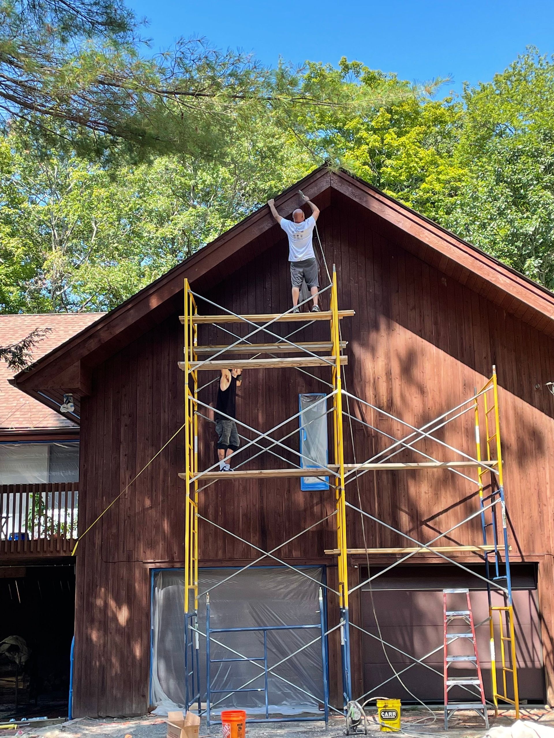 A man is standing on a scaffolding on the side of a house.