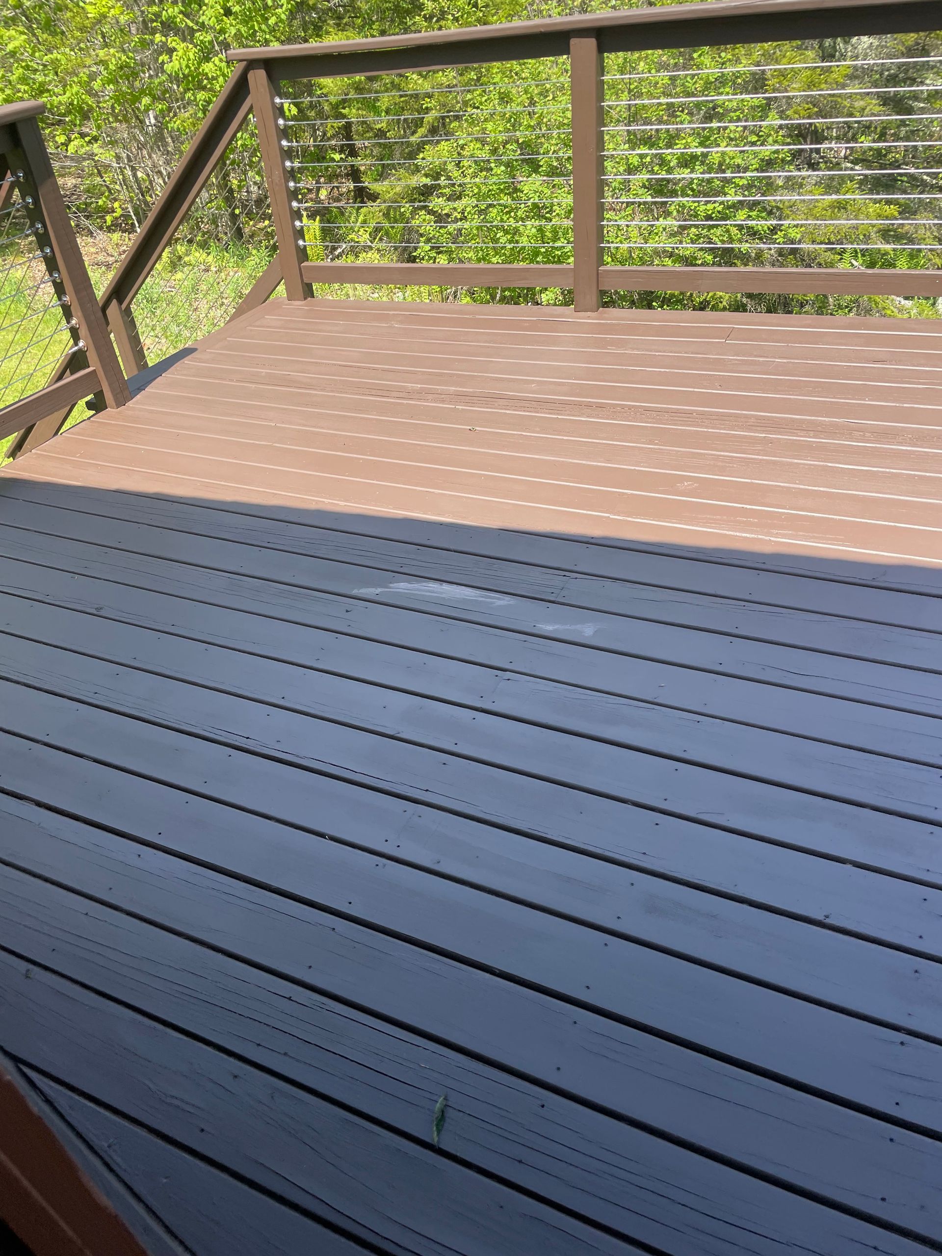 A wooden deck with a metal railing and trees in the background