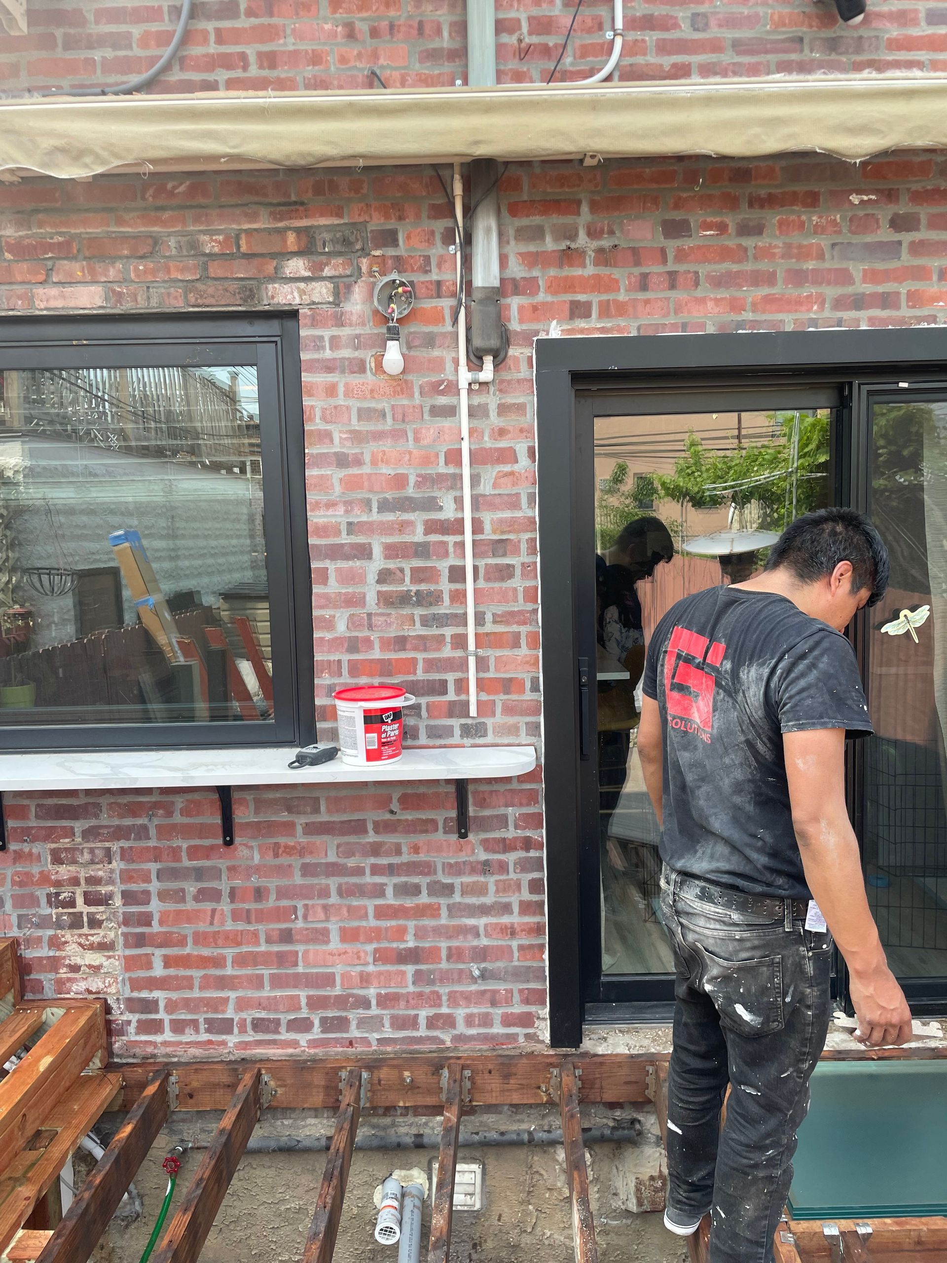A man is standing in front of a brick building.