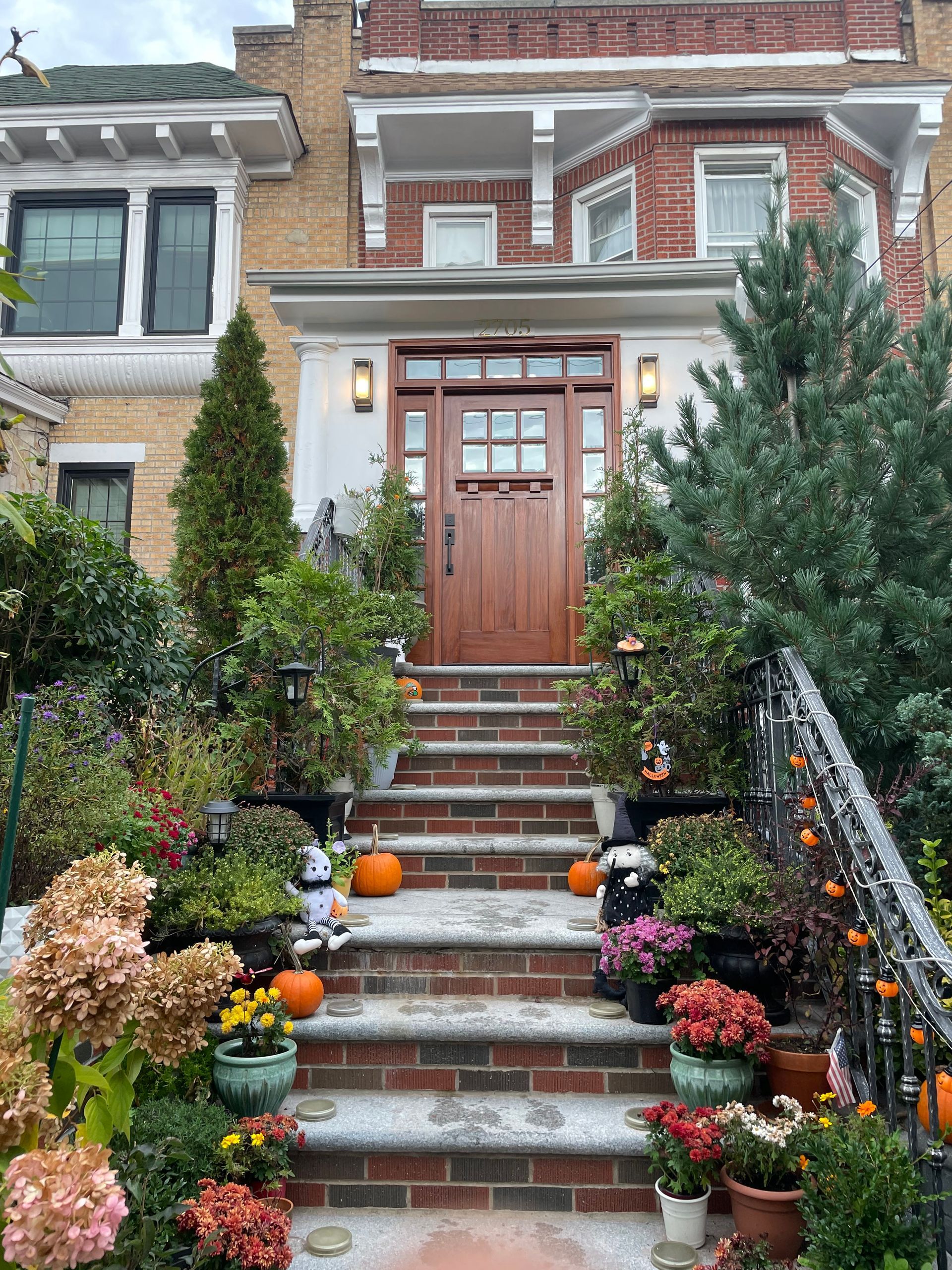 A brick house with stairs leading up to the front door decorated for halloween.